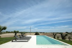 A minimalist villa with a concrete pool overlooking a vast agricultural landscape.