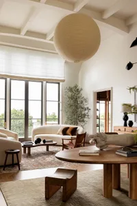A modern living room featuring a white sofa with brown cushions, a wooden table, a large spherical lamp, and a potted plant.