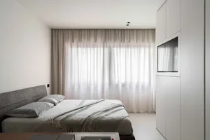 Modern minimalist bedroom featuring soft fabric curtains and sleek glass walls.