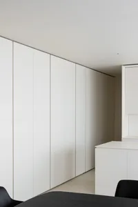 A minimalist bedroom featuring white cabinets against a white wall and floor.