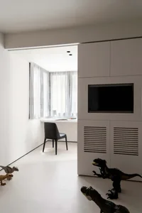 Minimalist children's room featuring a white window with sheer curtains, a black chair, and dinosaur figurines on the floor.