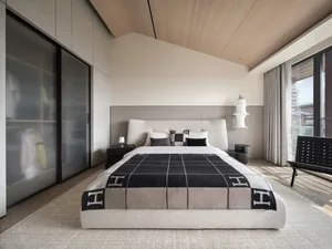 A minimalist bedroom featuring a bed with a light-colored headboard, a black and white checkered blanket, and a textured gray