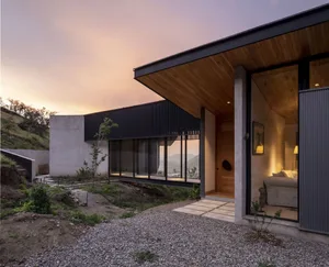 A minimalist home with concrete and glass exterior features a warm, cozy interior with modern design elements.