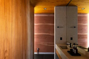 A modern bathroom featuring a concrete floor and walls, with a wooden ceiling and minimalist design.