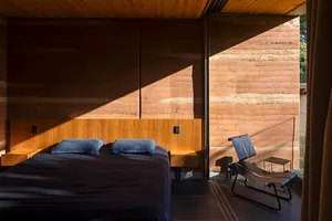 Contemporary bedroom featuring wooden bed frame and concrete wall