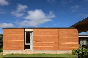 Modern house with wooden exterior panels under a blue sky with some clouds.