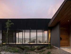 Modern exterior view of a house with a metal-clad exterior against a sunset sky.