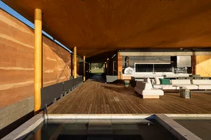 A modern outdoor living space featuring a wooden deck with outdoor seating and a kitchenette.