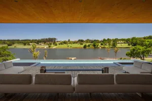 A modern, spacious living room with a large sofa overlooking a serene lake.