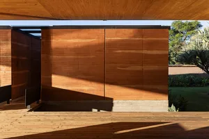 Modern wooden exterior house wall panels with natural light casting shadows on a porch