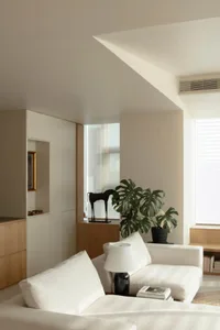 A minimalist living room with white furniture, a black horse statue, and a potted plant.