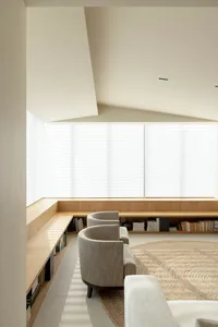 A minimalist living room featuring modern furniture, wood accents, and a circular jute rug, with a large window providing nat