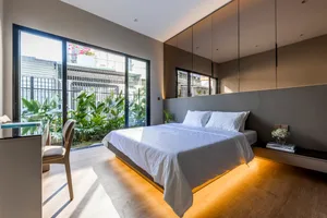 Modern bedroom with white walls, wooden flooring, and minimalist furniture.