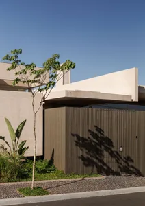 A modern building exterior with a concrete facade and a green tree in the foreground.