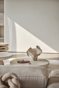 A modern, minimalist coffee table setting made of concrete with a decorative vase and cherries.