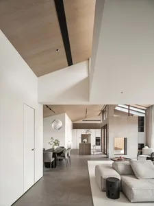 A minimalist modern living room with a concrete floor, industrial pendant light, and gray sectional sofa.