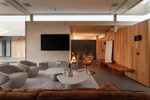 A modern living room featuring concrete walls, wooden accents, and marble coffee tables.