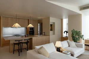 Modern living room and kitchen with wooden cabinets, metal kitchen island, and minimalistic design elements.