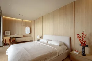 A minimalist bedroom with a large bed, white bedding, and a wooden wall paneling system.