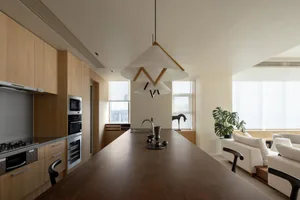 Modern minimalist kitchen featuring a large wooden countertop with a stainless steel sink and various kitchen appliances.