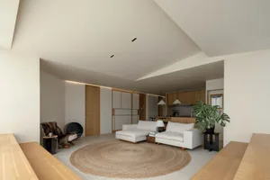 Modern minimalist living room with white sofas, wooden floor, and round rug.