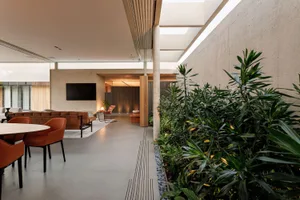 A modern room with concrete walls and floor, featuring a concrete dining table and chairs, and green plants