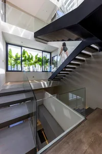 Modern staircase with glass railings and concrete steps, featuring a sleek and contemporary design.