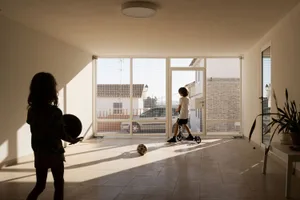 Children playing with a basketball and a scooter in an indoor space with ceramic flooring.