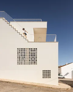 Modern exterior of a building featuring concrete stairs with an aluminum fence and a netted window.
