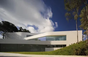 A modern residential house with concrete and glass exterior.
