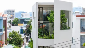 A modern residence featuring glass, concrete, and greenery elements.