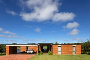 A modern residential building with a wooden exterior and a car parked in the driveway.