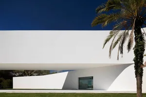 A modern house with a white concrete exterior and minimalist design.