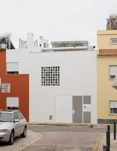 白色粉刷的住宅建築立面，搭配格子圖案窗戶與金屬裝飾。