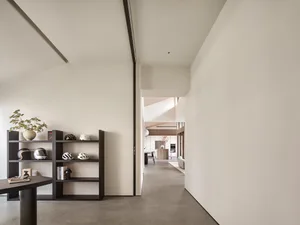 A minimalist home interior featuring a concrete floor and a modern shelving unit displaying decorative items and helmets.