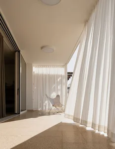 Modern white patio area with curtains and chair.