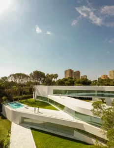 A modern villa with a white concrete exterior and large glass windows.