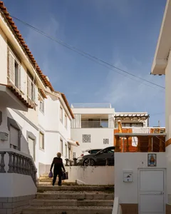 A residential street with concrete stairs, brick walls, and white-painted buildings in an urban setting.