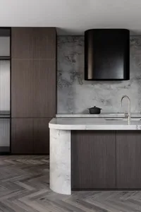 Modern industrial kitchen with a marble countertop, wooden cabinets, and concrete walls.