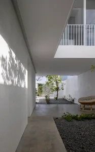 A minimalist house courtyard featuring a concrete patio and gravel garden.