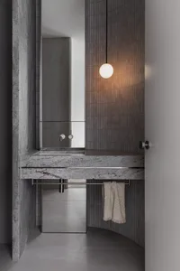 A modern bathroom with a granite countertop and a wall-mounted sink, featuring a minimalist design and concrete walls.