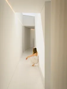 A minimalist interior space with concrete walls and floor, featuring natural light and geometric shapes.