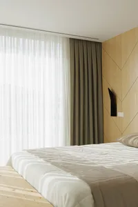 Modern minimalist bedroom with a bed covered in a fabric comforter and a wooden headboard