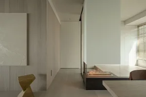 A modern minimalist living space featuring a wooden floor and walls, with a glass fireplace and abstract art.