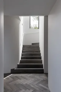 A modern staircase with white lighting fixtures and wooden steps, set against white walls.