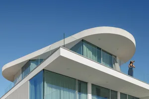 A modern house with a curved roof and glass walls.