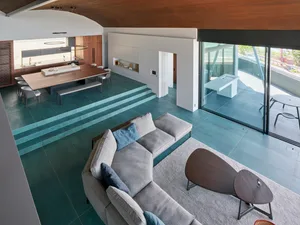 Minimalist living room with a concrete floor, a gray sectional sofa, and a wooden coffee table.