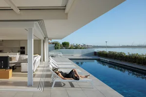 A minimalist residential patio featuring concrete flooring and glass elements.