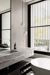 Modern bathroom interior featuring granite countertop and sink with vertical blinds and natural lighting.