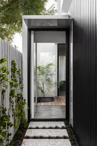 A modern entryway featuring a glass and metallic black door.